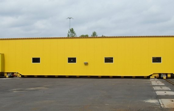 Waggonschiebebühne_mit_Einhausung_außerhalb_der_Produktionshallen_für_die_Versorgung_der_Lackierstraße_mit_Eisenbahnwaggons_bei_TVSZ